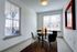 Bright and modern dining area with a stylish glass table and contemporary chairs, bathed in natural light streaming through large windows.