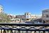 Vibrant urban view from balcony overlooking bustling shopping center with modern architecture and sunny blue skies.
