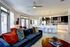 Modern open-concept living room with elegant decor, cozy seating, and a sleek kitchen with a breakfast bar.