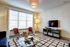 Bright and inviting living room featuring modern decor, large window with natural light, stylish seating, and a sleek TV setup.