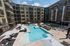 Luxurious apartment complex courtyard with inviting swimming pool, modern loungers, and elegant balconies, perfect for relaxation and leisure.