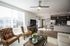 Bright, modern living room with cozy seating area, sleek kitchen, and large windows offering natural light.
