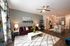 Modern open-concept living room with elegant decor, featuring a plush burgundy sofa, chic coffee table, vibrant abstract art, and a sleek kitchen with a breakfast bar.