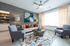 Contemporary living room with vibrant geometric rug, stylish gray armchairs, and elegant decor, bathed in natural light.