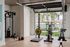 Modern gym space with state-of-the-art equipment and open view of a vibrant pool area surrounded by palm trees.