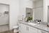 Elegant bathroom with granite countertop, sleek white cabinetry, and a spacious closet, exuding modern luxury and functionality.