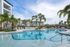 Luxurious apartment complex featuring a sparkling resort-style pool, surrounded by palm trees and elegant lounging areas.