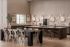 Elegant open kitchen with a large dining table, stylish bar stools, and artistic wall decor, inviting natural light.