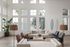 Bright and inviting living room with high ceilings, modern furniture, and large windows offering natural light and a beautiful view.