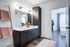 Bright modern bathroom with sleek cabinetry, double sinks, and stylish lighting, opening into a sunlit bedroom with large windows and elegant decor.