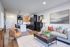 Modern open-concept living room with stylish furnishings, elegant lighting, and a sleek kitchen in the background.