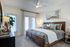 Elegant bedroom with modern decor, featuring a plush bed, stylish artwork, and ample natural light through large windows.