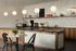 Chic modern kitchen featuring elegant pendant lighting, a stylish coffee setup, and cozy breakfast nook with wood accents and sleek cabinetry.