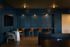 Elegant lounge area with rich blue paneling, featuring cozy seating and a sleek marble table, perfect for relaxed social gatherings.