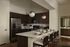 Sleek modern kitchen featuring dark wood cabinets, stainless steel appliances, and elegant pendant lighting with a spacious breakfast bar.