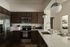 Modern kitchen with sleek dark wood cabinets, stainless steel appliances, and elegant pendant lighting, featuring a spacious kitchen island and polished countertops.