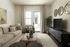 Elegant living room with cozy beige sofa, stylish decor, and large flat-screen TV, enhanced by natural light and a serene color palette.