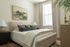 Inviting bedroom with a plush bed, modern decor, and a large window filling the room with natural light.