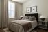 Inviting bedroom with cozy elegance, featuring soft lighting, plush bedding, and tasteful decor accents.