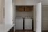Modern laundry room with sleek washer and dryer, open shelving, and ample space for storage.