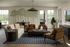Elegant living room with modern decor, featuring a cozy beige sofa, stylish brown leather chairs, and a chic wooden coffee table. Large windows offer abundant natural light and a serene outdoor view.