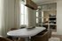 Elegant dining area with a modern oval table, plush leather chairs, and artistic wall mirrors enhancing the room's spaciousness.