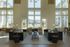 Elegant apartment lounge with high ceilings, large windows offering a scenic view, stylish sofas, and ambient lighting for a luxurious living experience.