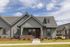 Charming modern suburban home with a cozy front porch, elegant grey siding, and well-maintained landscaping under a bright, blue sky.