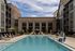 Luxurious apartment complex featuring a pristine outdoor pool, stylish loungers, and modern architecture under a bright blue sky.