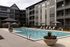 Luxurious apartment complex showcasing a modern pool area with comfortable lounge chairs, vibrant flower pots, and elegant building architecture.