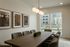 Modern dining room featuring a sleek wooden table, elegant chairs, and large windows with garden views, accented by contemporary artwork and stylish pendant lighting.