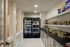 Elegant pantry with modern lighting, double-door coolers for beverages, and neatly organized shelves filled with snacks and essentials.
