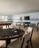 Luxurious recreation room featuring a poker table, pool table, and foosball table in an elegant, open setting.