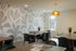 Chic and modern dining area with artistic wallpaper, elegant wooden tables, and plush seating under a stylish amber pendant light.