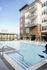 Modern apartment complex with spacious balconies overlooking a luxurious outdoor pool and sun deck.