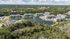 Aerial view of a tranquil apartment complex featuring lush greenery, scenic pond with a fountain, and a luxurious pool area.
