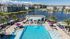 Luxurious apartment complex with stunning poolside views, vibrant sun umbrellas, and serene lake backdrop.