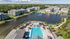 Luxurious apartment complex with scenic lake views, featuring a sparkling swimming pool, vibrant poolside cabanas, and lush greenery.