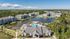Aerial view of luxury apartment complex featuring modern buildings surrounded by tranquil lakes and scenic greenery, with a vibrant community pool at the center.