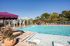 Luxurious pool area with sun loungers, chic pergolas, and lush greenery creating a serene oasis vibe.