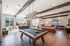 Luxurious open-concept living space featuring a modern billiard table, stylish seating areas, and contemporary lighting. Perfect for entertainment and relaxation.