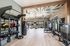 Contemporary home gym with floor-to-ceiling windows, featuring state-of-the-art equipment, vibrant wall design, and bright natural lighting.