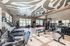 Modern fitness center with state-of-the-art equipment, vibrant zebra-patterned ceiling, and large windows for natural sunlight.