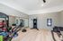 Modern apartment gym featuring state-of-the-art exercise equipment, a mirrored wall, and stylish wood flooring.