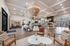 Elegant and spacious living area with modern decor, showcasing high ceilings, a large central chandelier, comfortable seating, and contemporary art in a bright and welcoming setting.