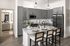 Modern kitchen with sleek granite countertops, gray cabinets, island seating, and stainless steel appliances.