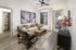 Modern living room with elegant decor, plush seating, and a warm ambiance. Features abstract wall art, cozy armchair, and natural light from large windows.