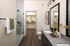 Chic modern bathroom with elegant granite countertops, dual sinks, and a spacious glass-enclosed shower adjacent to a walk-in closet.