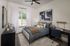 Elegant bedroom with modern decor, featuring a cozy bed, stylish artwork, and a functional study desk, bathed in natural light from a large window.