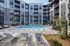 Modern apartment complex featuring a stunning outdoor pool with lounge chairs, surrounded by sleek multi-story buildings and vibrant landscaping.